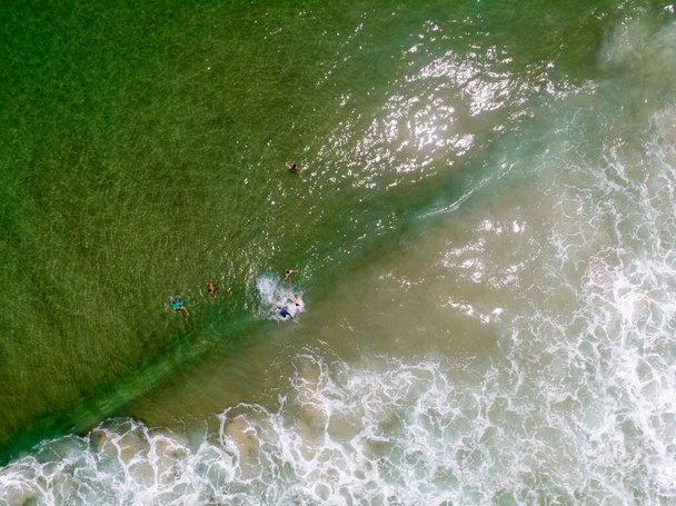 Вид з повітря на людей, які купаються в морі біля піщаного пляжу
 - Фото, зображення