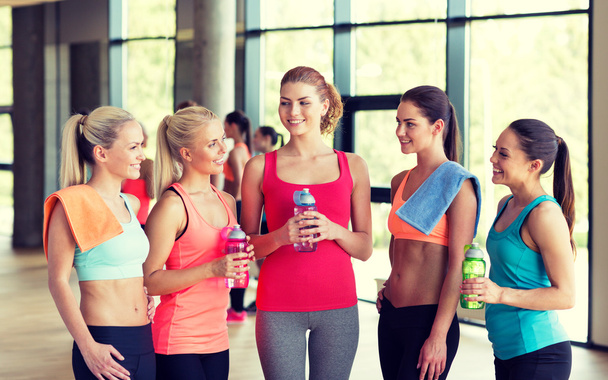 women with bottles of water in gym - Foto, afbeelding
