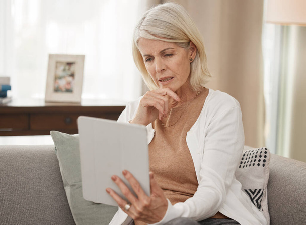 If you dont know get informed. a mature woman using a digital tablet and looking concerned at home - Foto, imagen