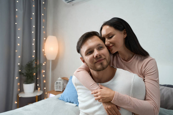 Young couple participates in a family romantic photo session in a cozy, bright bedroom decorated with lamps and garlandsamily - Foto, imagen