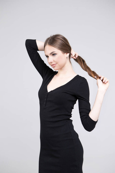 Skinny model in strakke zwarte jurk. Portret van een meisje met een schone huid en lang haar - Foto, afbeelding