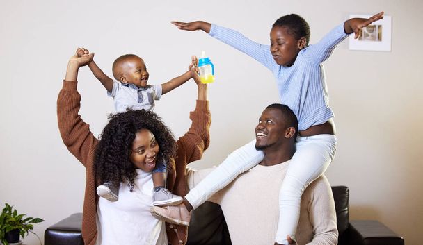 They keep us on our toes. two young parents bonding and playing with their children in the living room at home - Photo, Image