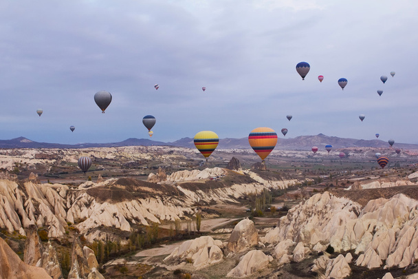 У Каппадокії (Туреччина) над гірським ландшафтом пролітає повітряна куля. - Фото, зображення