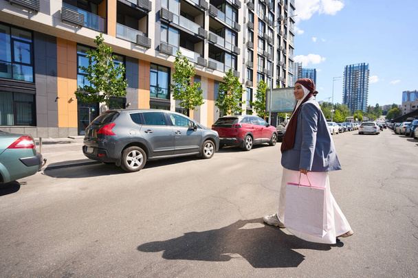 Tyytyväinen arabi nainen menee autoon ostoskassit - Valokuva, kuva