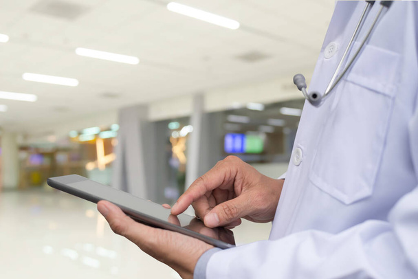 Doctor using digital tablet computer with blurred hospital background. - Foto, Bild