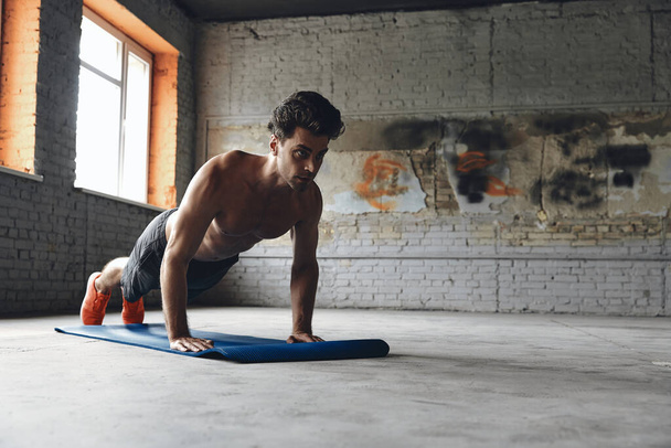 Confident young man doing push-up exercises in gym - Foto, Imagen