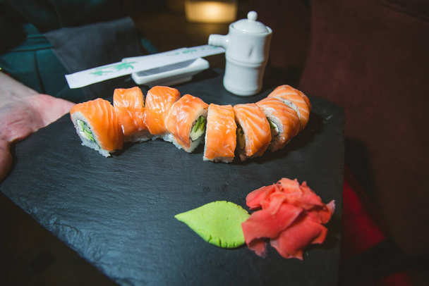 Philadelphia sushi roll with salmon, cucumber, avocado, cream cheese. Sushi menu. Japanese food. On a plate. On dark background. High quality photo - Fotografie, Obrázek