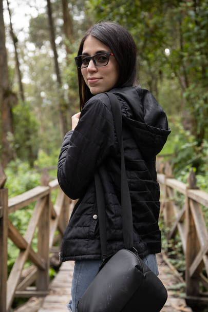 beautiful young woman with black straight hair wearing glasses, beauty, walking in the middle of a park with nature, casual lifestyle - Foto, Imagem