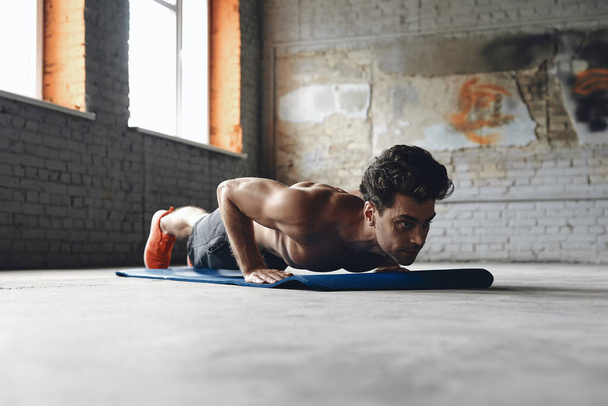 Confident young man doing push-up exercises in gym - Foto, immagini