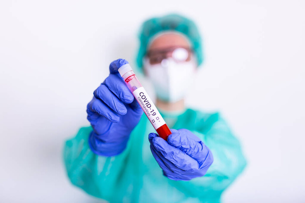 COVID-19, νόσος του ιού της κορώνας ή επιδημία του νέου κορωναϊού με γιατρό ή εργαστηριακό επιστήμονα σε εξοπλισμό ατομικής προστασίας του ΜΑΠ που διεξάγει εξέταση σωληναρίων αίματος σε νοσοκομειακό εργαστήριο - Φωτογραφία, εικόνα