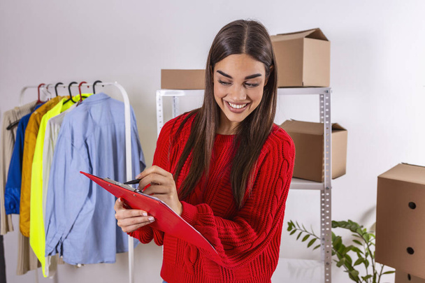 Start up. Young woman holding clip board after new order from customer . Delivery parcel boxes, small business owner working at home office, shopping online concept - Φωτογραφία, εικόνα
