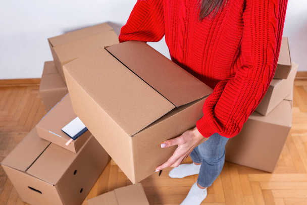 Young woman moving in into new apartment. House moving concept. Woman holding box. - Photo, Image