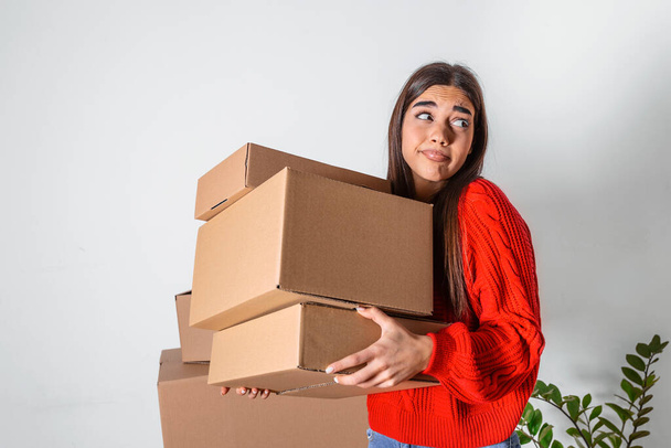 Young woman just moved in into new empty apartment unpacking and cleaning - relocation. Young girl carrying cardboard boxes at new home.Moving house. - 写真・画像