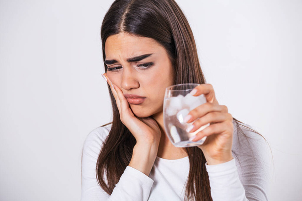 Young woman with sensitive teeth and hand holding glass of cold water with ice. Healthcare concept. woman drinking cold drink, glass full of ice cubes and feels toothache, pain - Foto, imagen
