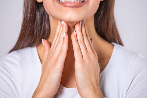 Close up of young woman rubbing her inflamed tonsils, tonsilitis problem, cropped. Woman with thyroid gland problem, touching her neck, girl has a sore throat - Photo, image