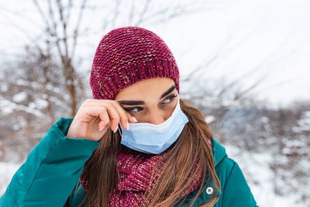 Avoid touching your eyes. Woman wearing face mask rubbing her eye outdoor. Young woman touching her eye with dirty hand. Don't touch your face, stop spreading Coronavirus - Zdjęcie, obraz
