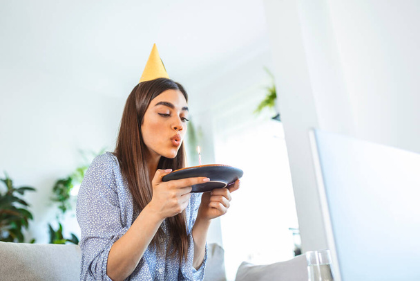 New normal concept. Happy woman celebrating her birthday alone. young woman holding a cake. Birthday party at home. Family video call. Social distancing. Life at home. making a wish - Fotografie, Obrázek