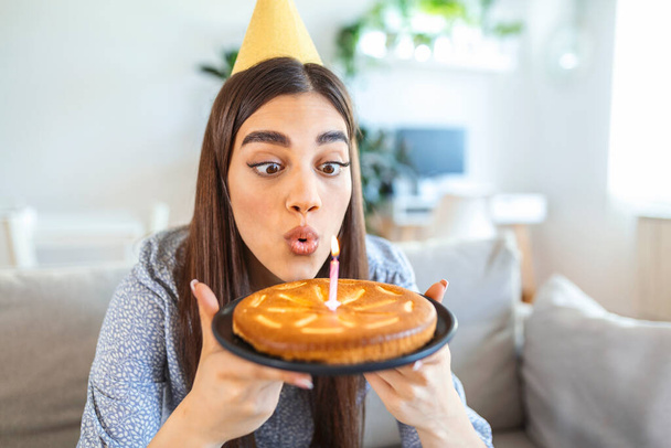 New normal concept. Happy woman celebrating her birthday alone. young woman holding a cake. Birthday party at home. Family video call. Social distancing. Life at home. making a wish - Foto, Imagem