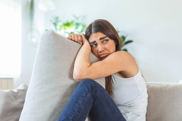 Difficult times. Portrait of a cheerless sad caucasian woman holding her hands crossed and hugging big pillow while thinking about her problems. Stock photo - Photo, Image