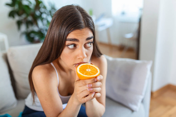 Nemocná žena, která se snaží vycítit vůni napůl čerstvé pomeranče, má příznaky Covid-19, infekce virem korony - ztrátu čichu a chuti. Jedním z hlavních příznaků onemocnění. - Fotografie, Obrázek