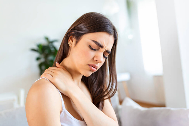 Tired woman massaging stiff sore neck, tensed muscles fatigued from computer work in incorrect posture while feeling hurt joint shoulder back pain ache. Fibromyalgia concept - Photo, Image