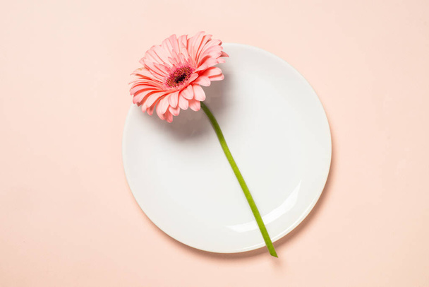 White plate and pink flower. Spring or summer table setting. Top view. - Foto, Imagem