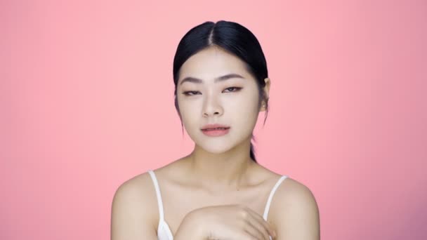 Close-up perfecte schoonheid gezicht van jonge mooie Aziatische vrouw massages haar gezicht zachtjes met vingertoppen. Reclameconcept voor gezichtscrème. - Video