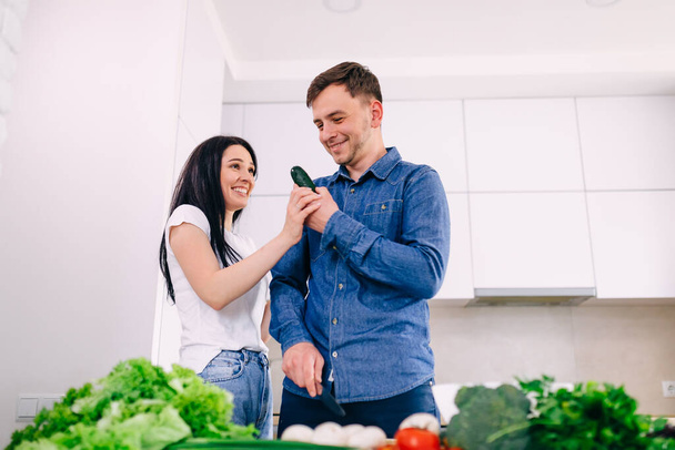 Young happy couple are enjoying and preparing healthy food in their kitchen. - Fotoğraf, Görsel