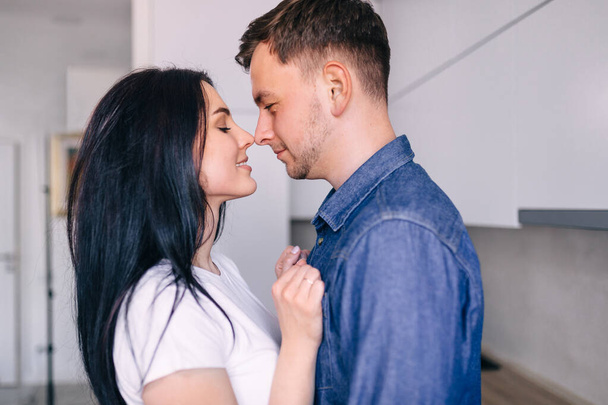 Cute husband and wife tenderly embrace each other in a beautiful kitchen - Fotografie, Obrázek