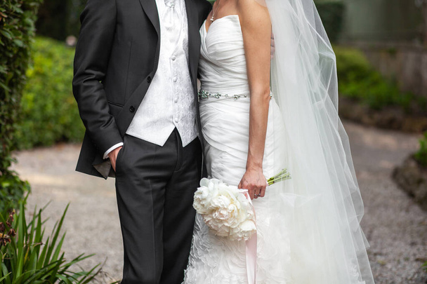 Невеста со свадебным букетом и женихом на прогулке. - Фото, изображение