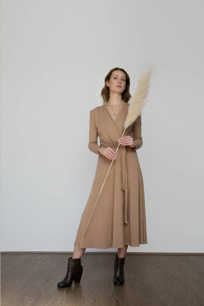 Serie of studio photos of young female model in beige viscose wrap dress. - Valokuva, kuva