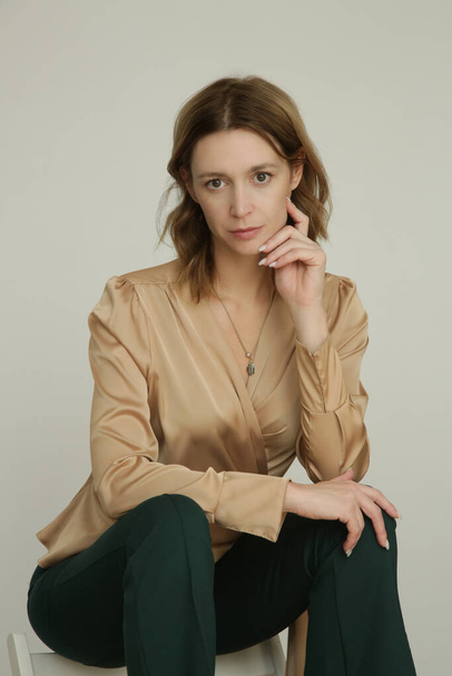 Serie of studio photos of young female model in golden colored top and pine green skinny trousers - Zdjęcie, obraz