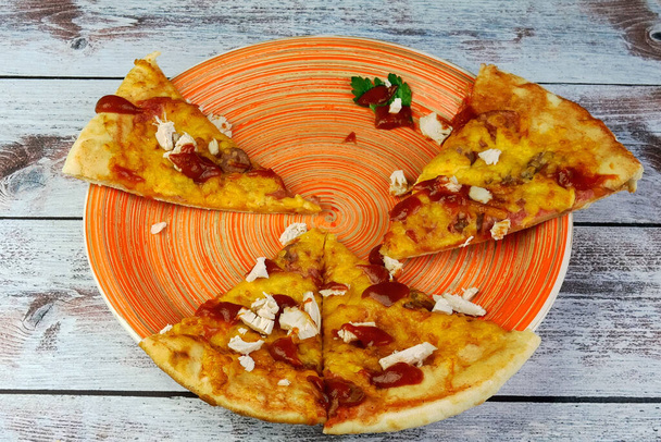 Half-eaten homemade pizza with cheese, chicken meat, olives, ketchup on plate. Tasty unhealthy fast food snack of Mediterranean food. Close-up. - Foto, imagen