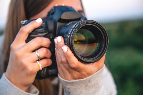 Молода жінка-фотограф з професійною камерою фотографується на природі, крупним планом
. - Фото, зображення