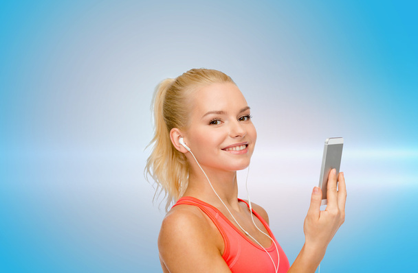 smiling sporty woman with smartphone and earphones - Valokuva, kuva