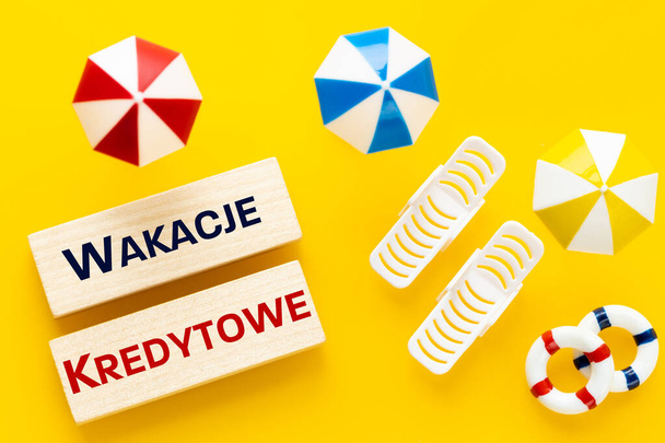  Wakacje Kredytowe in Poland, Loan Holidays Written in Polish, Miniature sunbeds, umbrellas on the beach, Creative concept, Polish social program that allows you to take a vacation from paying home loan installments - Φωτογραφία, εικόνα