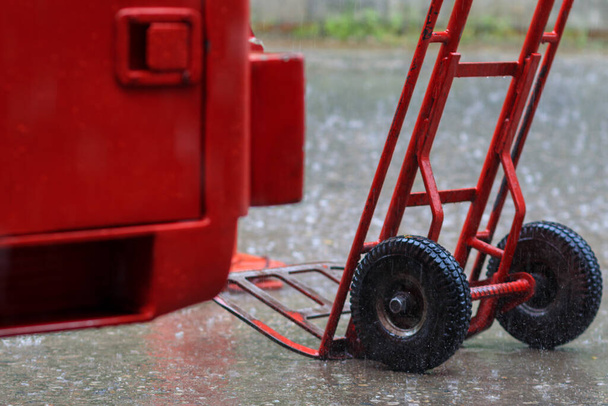 Kırmızı araba yağmurda park edilmişti çünkü markete mal taşımak için hazırlanmıştı, ama sağanak yağmur yağdığında mallar durduruldu ve araba yağmurda terk edildi.. - Fotoğraf, Görsel