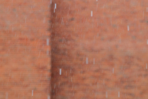 background blurs orange wall on day when it rains heavily during  rainy season and there is forecast warning of heavy rain. Blurred background of orange brick wall on rainy day and copy space for text. - Foto, Imagen
