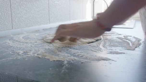Cook rolls out the dough for pizza with a rolling pin. The cook rolls out the dough, chef is baking, bakery products, making the dough - Filmati, video