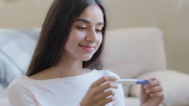 Portrait of joyful happy pregnant woman future mom sits at home holds pregnancy positive test result. Beautiful arabian latino young housewife expecting baby anticipate childbirth planning parenthood - Séquence, vidéo