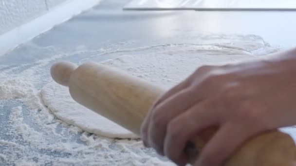 Cook rolls out the dough for pizza with a rolling pin. The cook rolls out the dough, chef is baking, bakery products, making the dough - Кадри, відео