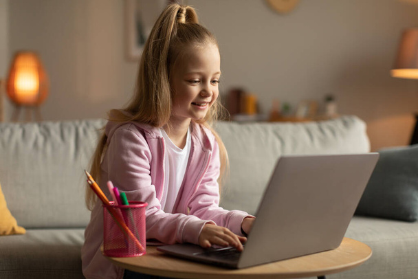 E-oppiminen. School Kid Girl Kirjoittaminen käyttäen Laptop Learning Online istuu sohvalla kotona. Koulutyttö selaamassa Internetiä tekemässä läksyjä. Etäopetuksen käsite - Valokuva, kuva