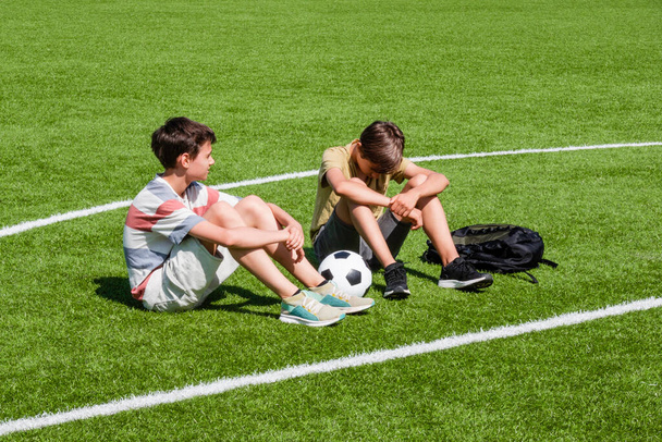 Teenage boy comforting consoling upset sad friend in school stadium. Education, bullying, conflict, social relations, problems at school, learning difficulties concept. - Foto, imagen