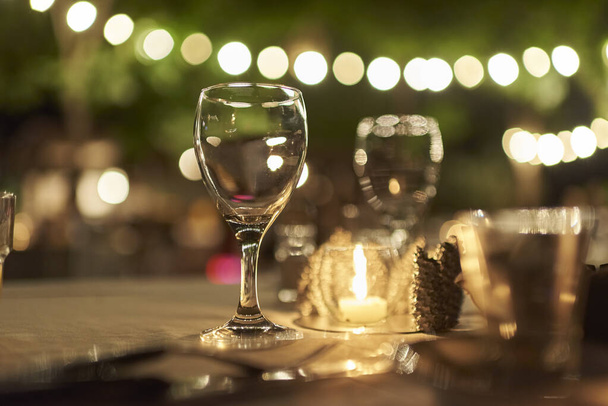 Ulkona juhla yö kohtaus, pöytä lasit ja kynttilä, koristelu merkkijonoja valot. - Valokuva, kuva