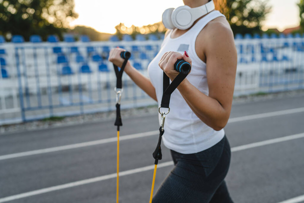 One woman training with elastic rubber resistance bands in stadium close up on hands selective focus copy space side view - Fotoğraf, Görsel