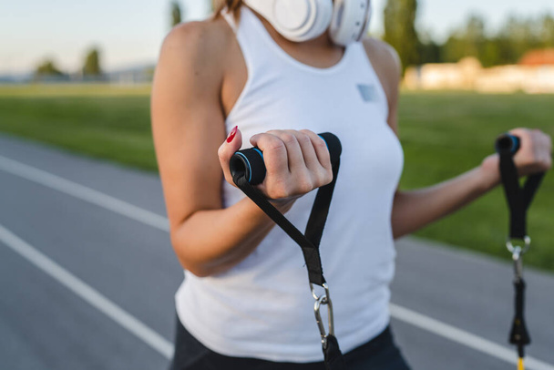 One woman training with elastic rubber resistance bands outdoor close up on hands selective focus - Fotoğraf, Görsel