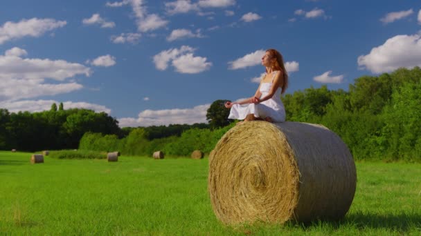 Attractive girl in a white dress on a haystack enjoys freedom. High quality 4k footage - Кадры, видео