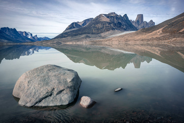 Granite tower of Mt.Asgard and surrounding peaks reflect in waters of Glacier Lake in remote arctic valley of Akshayuk Pass, Baffin Island, Canada. Silent moment far in the wilderness of the north - Foto, imagen