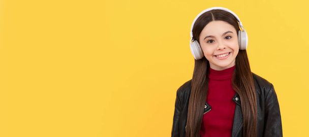 šťastná teen dívka poslouchat hudbu ve sluchátkách na žlutém pozadí s kopírovacím prostorem. Dětský portrét se sluchátky, horizontální plakát. Dívka poslouchající hudbu, banner s kopírovacím prostorem - Fotografie, Obrázek