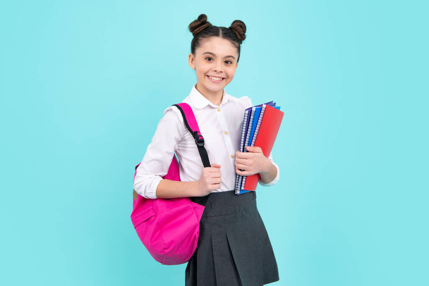Schoolgirl, teenage student girl hold book on blue isolated studio background. School and education concept. Back to school. Happy teenager, positive and smiling emotions of teen girl - Foto, Imagem